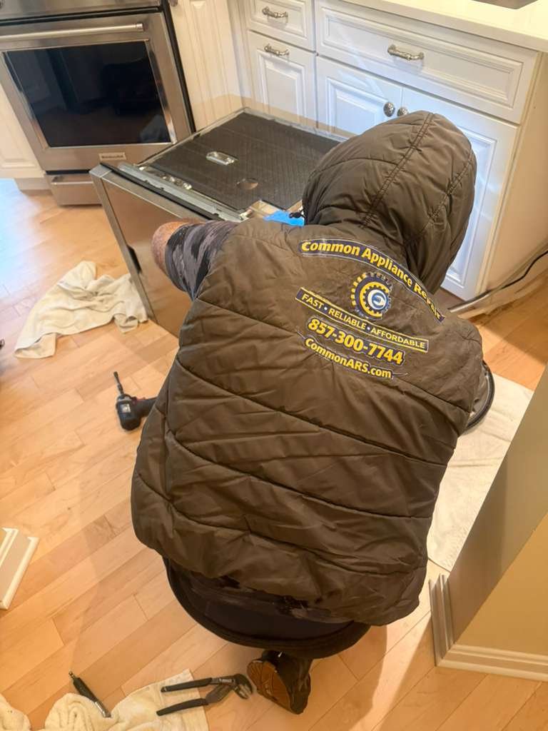 Technician working behind a refrigerator in a Boston kitchen