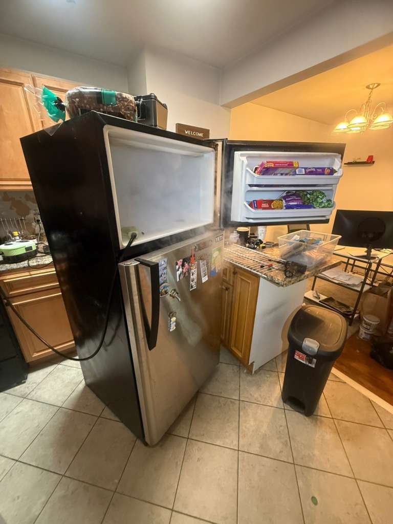 Refrigerator repair in progress on a hardwood floor
